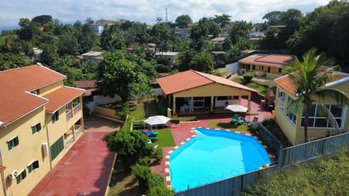 Equador Houses em São Tomé com chalés amarelos, telhados laranja, piscina azul-turquesa e ambiente tropical
