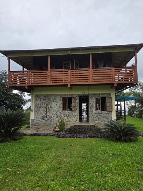 Quarto duplo Vila Paraíso na Equador Houses em São Tomé, com deck de madeira, muros de pedra e jardim com vista para o mar