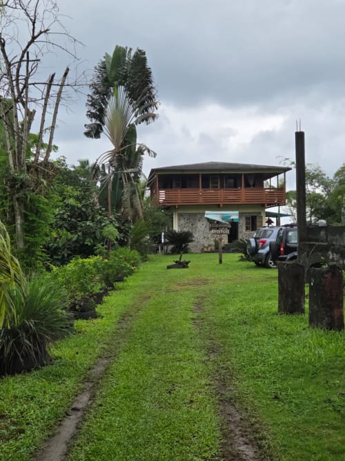 Casarões Equador Vila Paraíso em São Tomé, bungaló elevado em madeira com vista para o jardim, cercado pela vegetação tropical