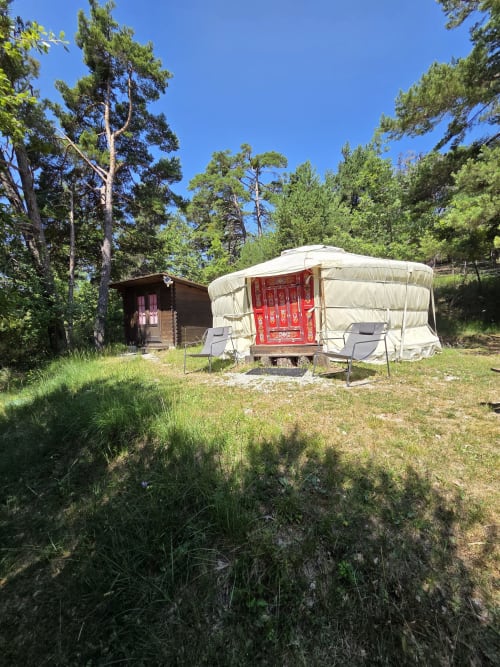 Yurt accommodations at Destination Ailleurs in Castellane with deck chairs, forest views