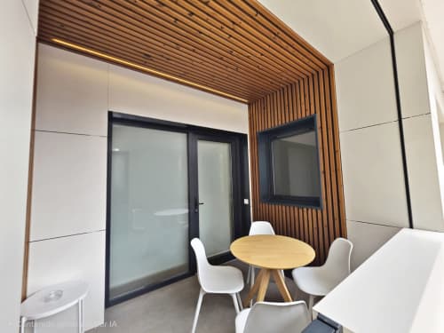 Sala de reuniones moderna en BR Silgar, Sanxenxo con techo de lamas de madera, mesa redonda y sillas blancas