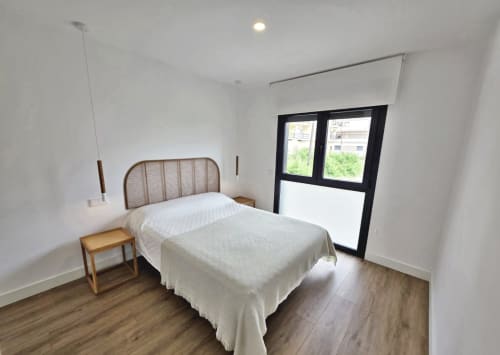 Habitación moderna en BR Silgar Sanxenxo con cama, mesita de noche de madera y puertas negras hacia la terraza