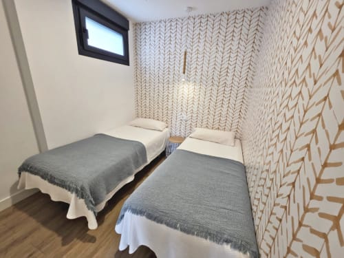 Dormitorio doble en apartamento BR Silgar de Sanxenxo con papel pintado estampado y ventana