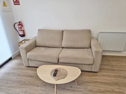 Sofá beige con mesita de madera en apartamento BR SILGAR, Sanxenxo, con chimenea y equipos de seguridad