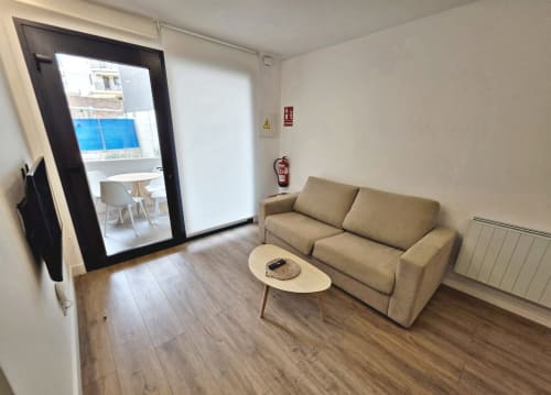 Sala de estar moderna del apartamento BR Silgar en Sanxenxo con sofá beige, televisor y acceso a balcón