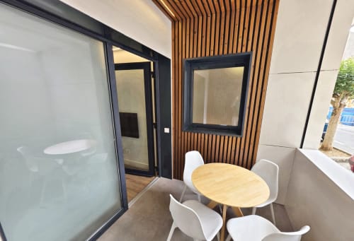 Comedor moderno con pared de listones de madera, mesa redonda y sillas blancas en BR SILGAR, Sanxenxo