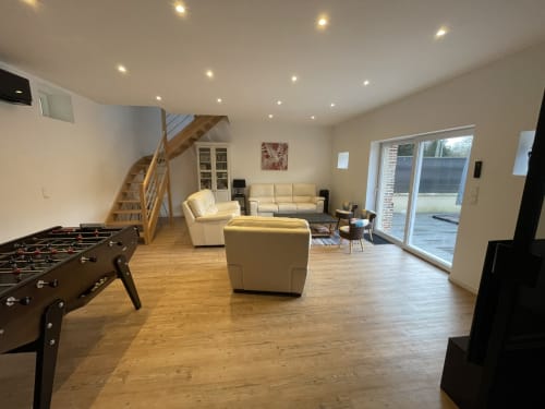 Le Bovary villa living room with foosball, cream seating, wooden stairs, and garden view doors at Les Gites De Flaubert