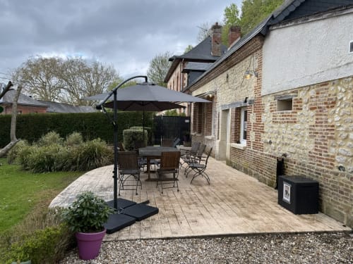 Garden patio at Les Gites De Flaubert cottage with umbrella, dining table, and brick exterior in Le Héron