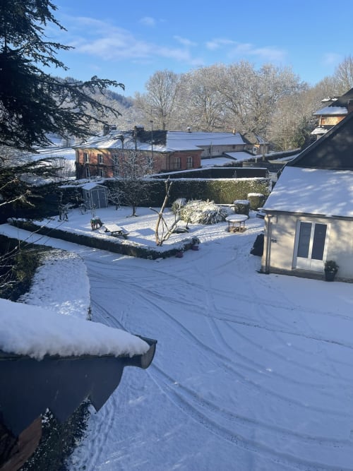 Snowy winter garden view at Les Gites De Flaubert cottage, Le Héron France with brick buildings