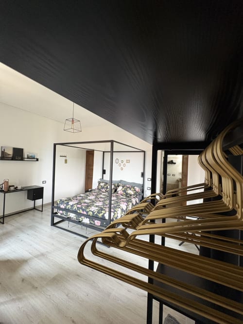 La camera da letto La Dolce Casa a Cremia con letto a baldacchino, biancheria floreale, sedie in legno e soffitto nero