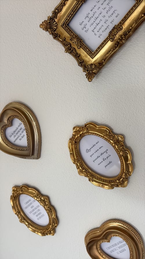 Cornici dorate ornamentali con poesia italiana manoscritta su muro bianco a La Dolce Casa, Cremia