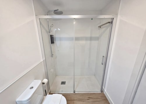 Baño moderno con ducha de cristal en el apartamento BR Silgar en Sanxenxo, con azulejos blancos y diseño contemporáneo
