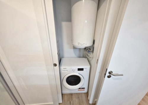 Lavadero con lavadora blanca y calentador de agua en el apartamento BR SILGAR, Sanxenxo