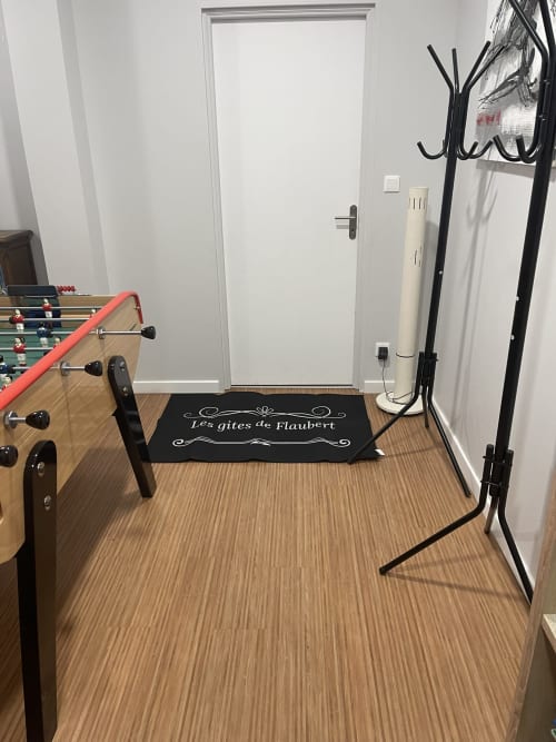 Recreation room at Les Gites De Flaubert villa with foosball table, black coat stand, and entrance door on wooden flooring