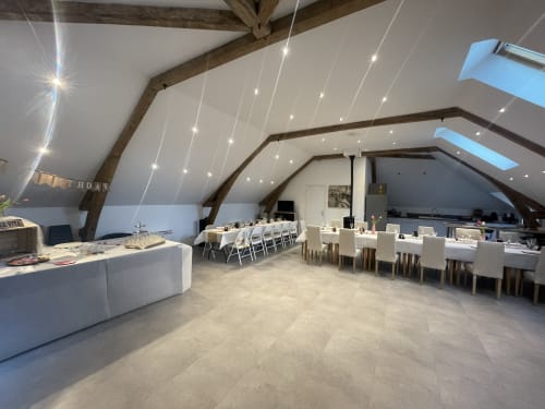 Modern attic dining and lounge space at Les Gites De Flaubert villa with exposed beams, skylight, and elegant white