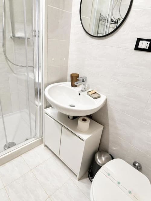 Modern bathroom at Vatican Living Rome with white tile walls, round sink, shower enclosure, and toilet in Rome B&B