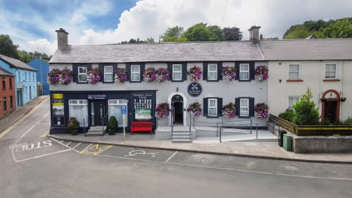 Madeline's Accommodation hotel in Wicklow with charming black and white facade, vibrant hanging baskets, and colorful nearby