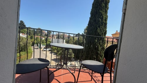 Balcon de la Résidence Kimi à Cannes avec carrelage en terre cuite, table, chaises et vue sur le jardin