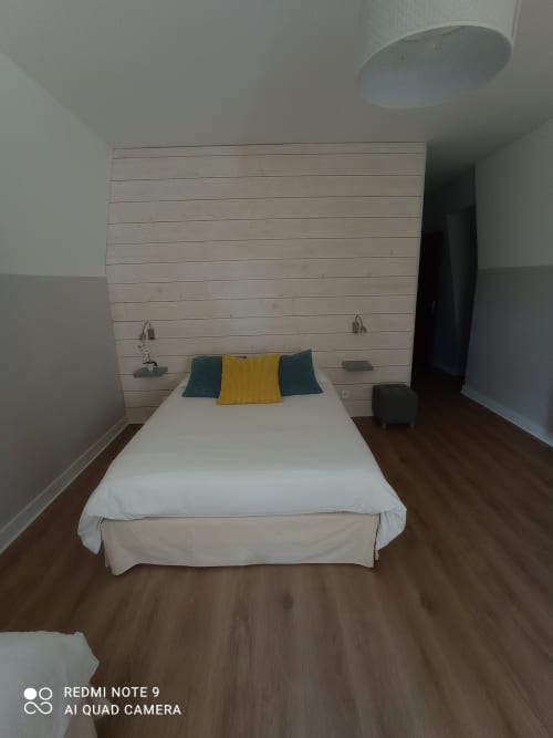 Chambre au gîte Le Clos Gaillardou à La Roque-Gageac avec lit blanc, oreillers jaunes et bleu-vert, tête de lit en bois