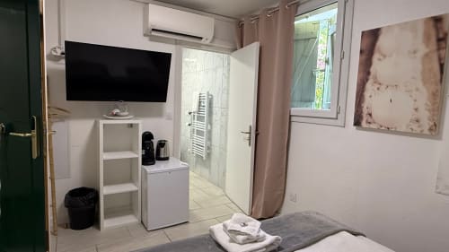 Chambre moderne à Kimi Résidence Cannes avec TV écran plat, rangements blancs, salle de bain rénovée et carrelage