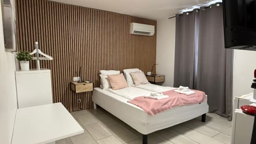 Chambre Double Deluxe à Kimi Résidence à Cannes avec lit queen-size, mur d'accent en lattes de bois, TV écran plat et mobilier moderne