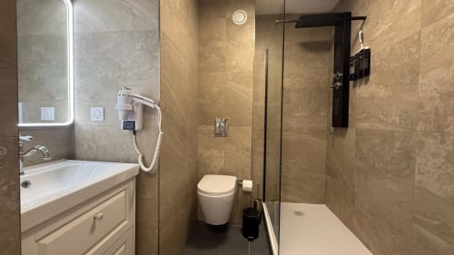 Salle de bains moderne de la Kimi Résidence Cannes avec douche carrelée, toilettes et miroir éclairant