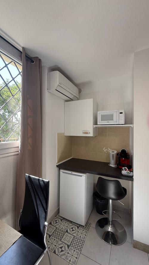 Petite kitchenette équipée à la Résidence Kimi Cannes avec micro-ondes, réfrigérateur et plan de travail noir
