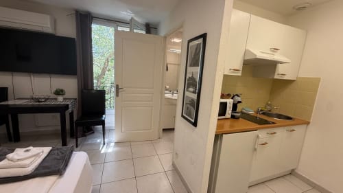 Kitchenette studio à la Kimi Résidence Cannes avec séjour, TV et accès à la vue sur le jardin