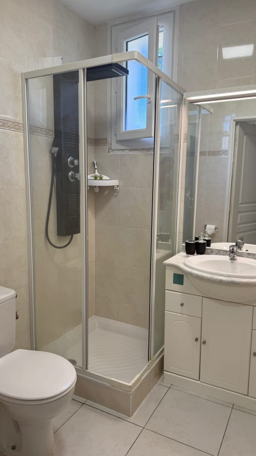 Salle de bain moderne à la Kimi Résidence à Cannes avec douche vitrée, lavabo blanc et toilettes