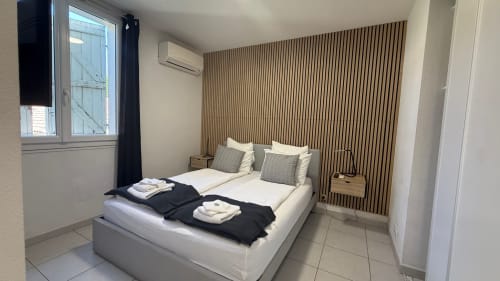 Chambre moderne à la Résidence Kimi à Cannes avec lit blanc, mur en bois et vue sur le jardin
