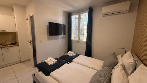 Studio à la Kimi Résidence à Cannes : lit double, kitchenette, TV et vue sur le jardin par portes vitrées