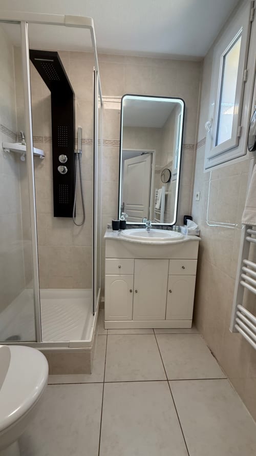 Salle de bain moderne du studio Kimi Résidence Cannes avec douche à l'italienne, vasque, miroir LED et carrelage