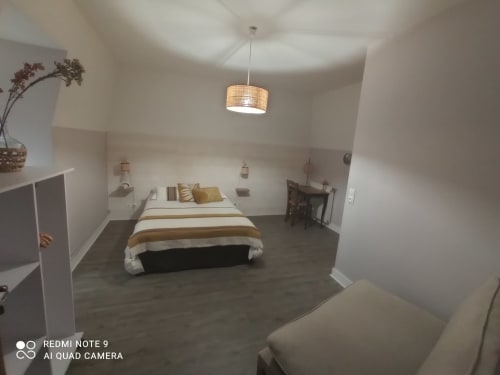Spacieuse chambre double au B&B Le Clos Gaillardou avec literie rayée, luminaires suspendus, parquet et vue sur le jardin