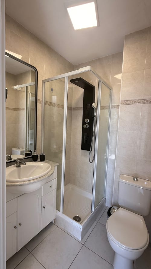 Salle de bain moderne à la Résidence Kimi à Cannes avec douche, vasque ronde, toilettes et éclairage LED au plafond