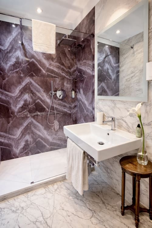 Bagno moderno dell'Hotel Ariel Silva Venezia con doccia in marmo viola, lavabo bianco, pavimento in marmo e specchio illuminato