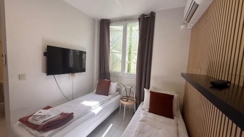 Studio Twin à la Kimi Résidence à Cannes avec deux lits, TV murale et portes donnant sur le jardin