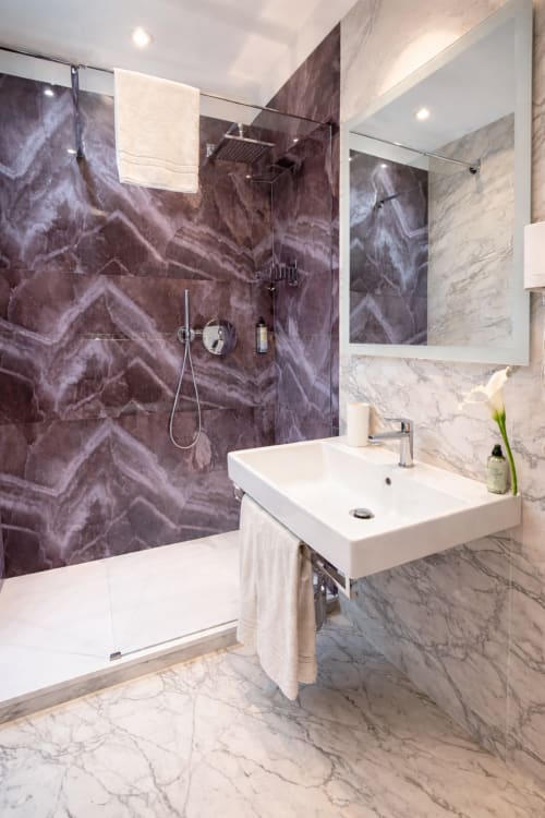 Bagno moderno di lusso in appartamento veneziano con doccia in marmo nero, pavimento in marmo bianco e lavabo in marmo