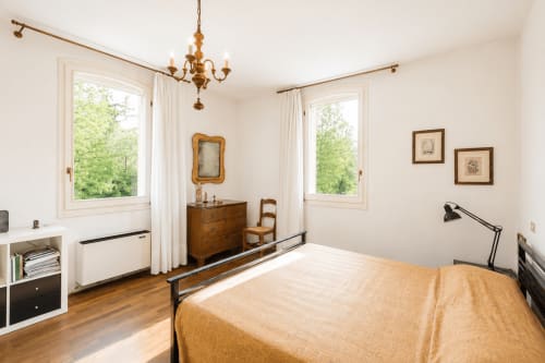 Camera luminosa a Palazzo Bonfiglioli con letto in legno, vista sul giardino, lampadario e arredi classici a San Giovanni in