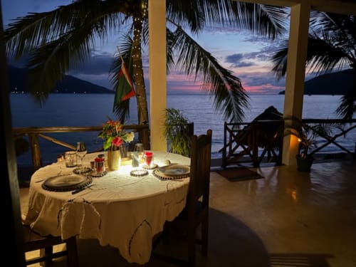 Dîner en bord de mer à Madabay's Lodge Nosy Be avec vue sur l'océan au coucher du soleil et palmes