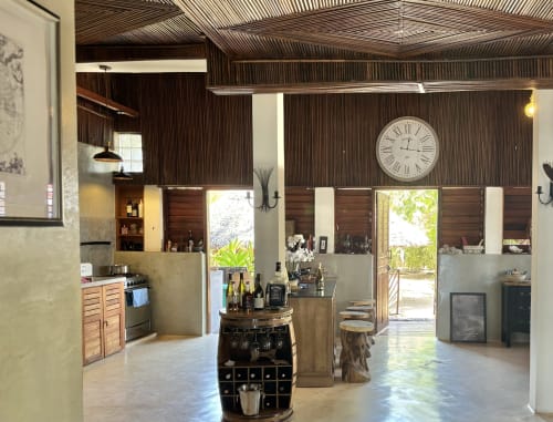 Cuisine ouverte et salle à manger du Lodge Nosy Be de Madabay avec finitions en métal ondulé, bar à vins et vue sur mer