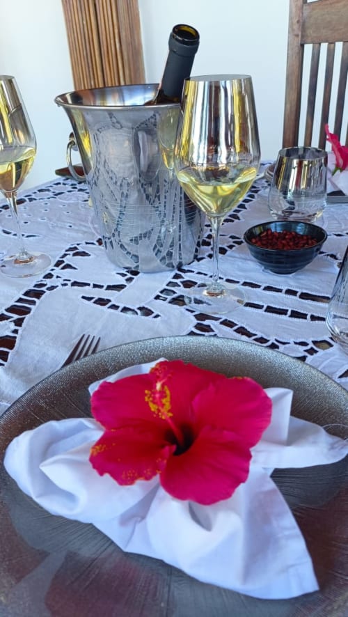 Élégant dîner en bord de mer à Madabay's Lodge Nosy Bé avec vin, fleur d'hibiscus rouge et vue océan