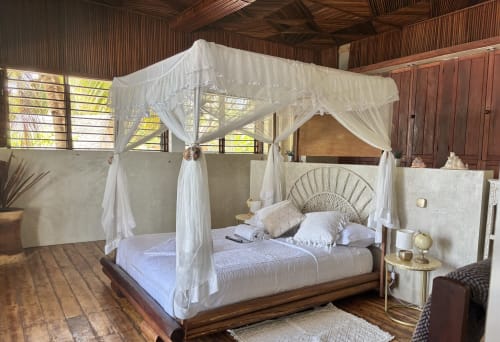 Lit à baldaquin de luxe aux voilages blancs dans la villa balnéaire du Lodge Nosy Be de Madabay, Madagascar