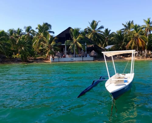 Bateau blanc ancré dans les eaux turquoise devant la plage de la villa Madabay's Lodge à Nosy Bé, Madagascar