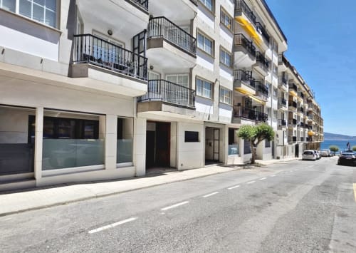 Exterior del hotel BR Silgar en Sanxenxo: moderno edificio de apartamentos blancos con balcones, locales comerciales en planta baja y vistas al océano