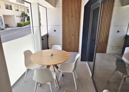 Zona de comedor del BR Silgar Club con mesa redonda de madera, sillas blancas y pared con listones de madera en Sanxenxo