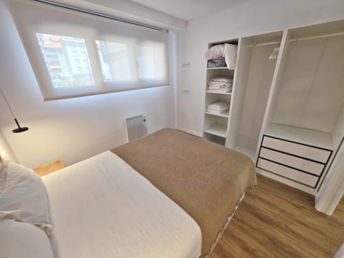 Habitación del BR Silgar Club en Sanxenxo con cama, armario empotrado, suelo de madera y ventana luminosa