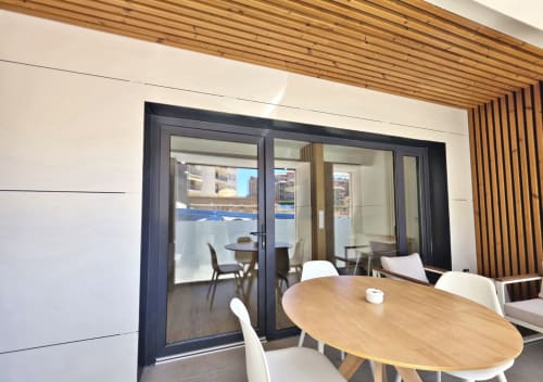 Comedor del Club BR Silgar con mesa redonda de madera, modernas puertas correderas negras que abren al balcón junto a la piscina en Sanxenxo