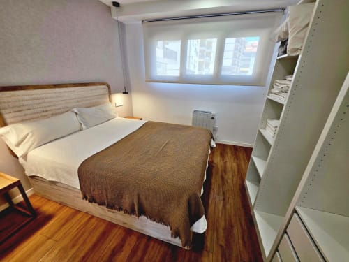 Habitación del Club BR Silgar en Sanxenxo con cama queen, suelos de madera, estanterías y vistas a la ciudad
