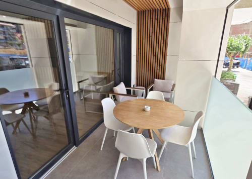 Zona de comedor del BR Silgar Club en Sanxenxo con mesa redonda de madera, sillas blancas y espacio lounge moderno