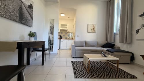 Séjour moderne à la Kimi Résidence à Cannes : canapé, table à manger, kitchenette et vue sur le jardin